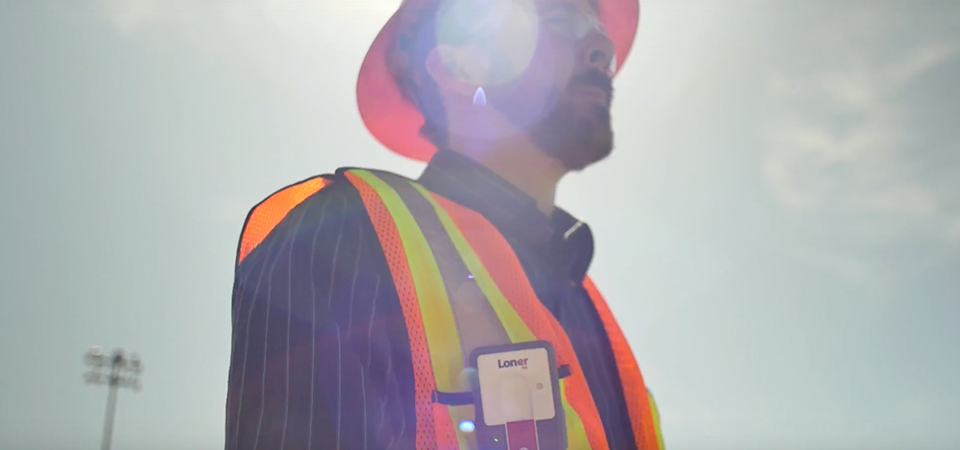 Dispositivo para trabajadores aislados Blackline Safety Loner M6 que lleva un empleado que trabaja bajo un sol abrasador.